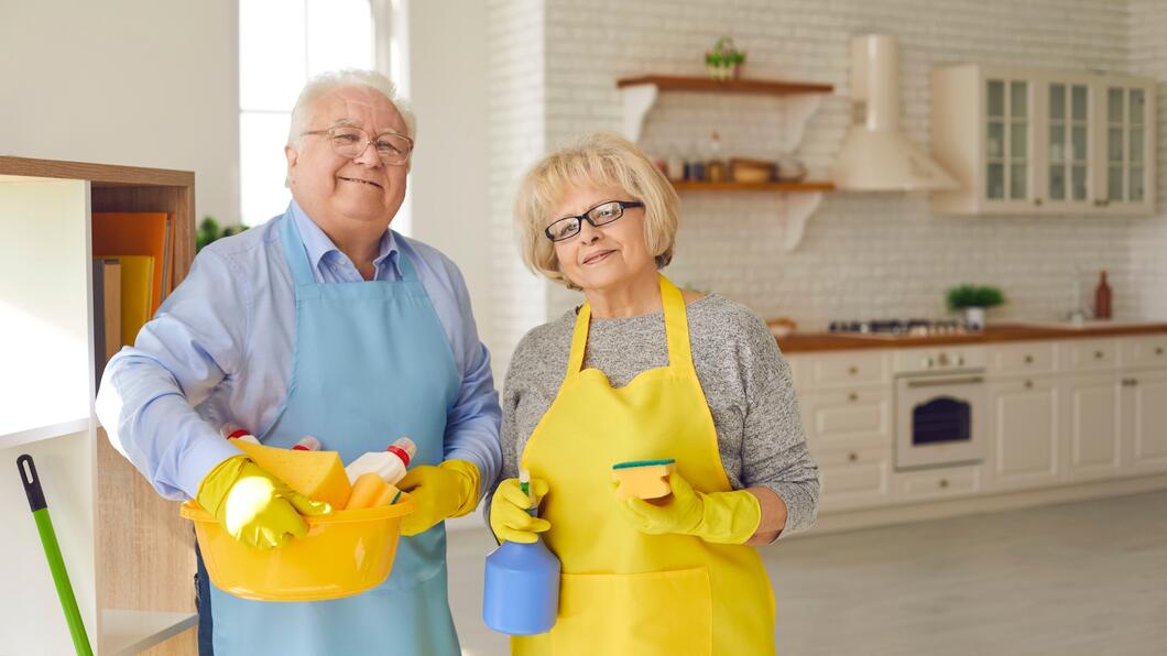 Twee ouderen met schoonmaakartikelen in de handen