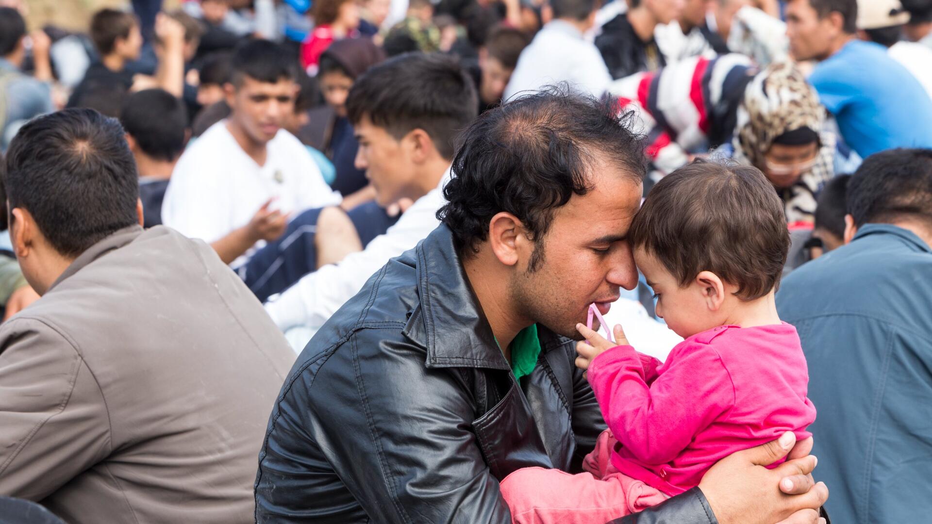 Man met kind in groep asielzoekers in Idomeni, Griekenland